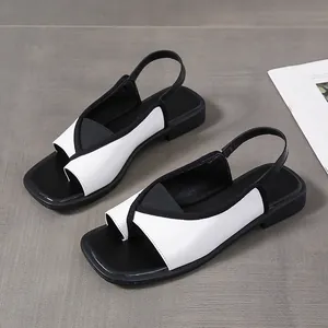 Detail view of chic black and white square toe slingback sandals with thong strap