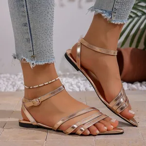 Detailed view of elegant rose gold flat sandals with pointed toe and ankle strap.