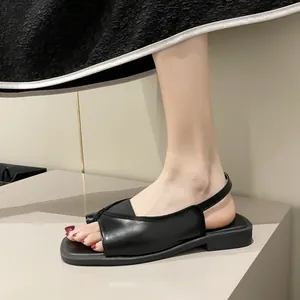 Detail of black square-toe thong sandals featuring a minimalist low-heel design.