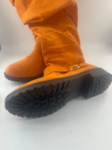 Close-up of orange suede slouchy boots featuring a thick non-slip lug sole design