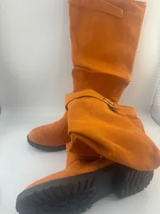Detail shot of orange faux suede slouchy tall boots featuring thick lug soles and chic design