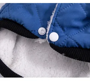 Close-up of blue quilted pet vest with warm white fleece lining and snap button closure.