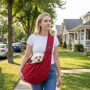 Outdoor lifestyle view of a red breathable pet sling bag with a small white dog inside.