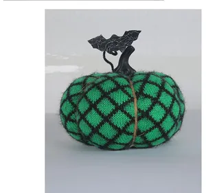 Detailed view of a handmade green knitted Halloween pumpkin with a bat ornament.