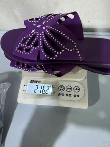 Primo piano di un sandalo a farfalla con strass viola che pesa 216,2 grammi su una bilancia