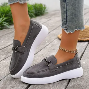 Dettaglio di mocassini in pelle scamosciata grigia con suola platform bianca e fibbia.