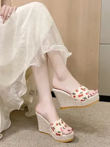 Détail de sandales compensées à motif cerise avec plateforme tissée et ouverte.