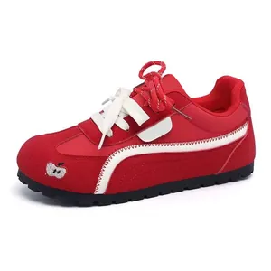 Vista laterale di eleganti sneaker rosse da donna con striscia bianca e dettaglio a mela ricamato