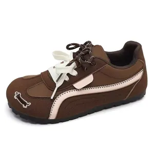 Dettaglio delle scarpe da ginnastica marroni da donna con ricamo a osso sulla punta.