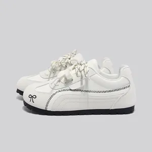 Sneakers bianche da donna stile tedesco con cuciture a zigzag nere e fiocco chic.