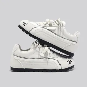 Sneaker bianche stile tedesco con cuciture a zigzag nere e ricamo a fiocco sulla punta
