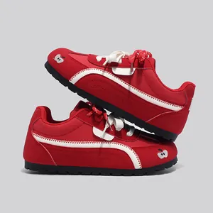 Vista dettagliata di sneaker rosse stile Trainer con ricamo a mela e striscia ondulata