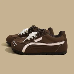 Dettaglio ravvicinato di sneaker marroni stile tedesco con ricamo di cagnolino.