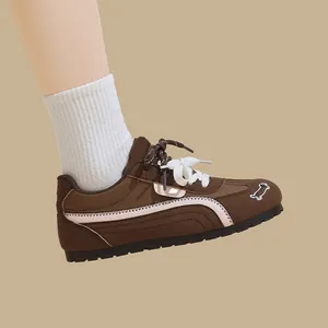 Dettaglio di sneaker GAT marroni eleganti con ricamo a forma di bassotto bianco sulla punta.