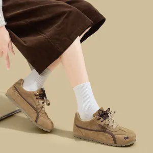 Primo piano di sneakers scamosciate marroni con calze bianche e gonna di velluto.