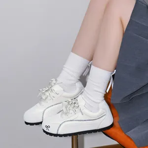 Dettaglio delle scarpe da ginnastica bianche da donna con fiocco nero ricamato
