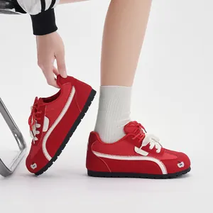 Dettaglio scarpe sportive rosse con ricamo mela e lacci bianchi per il tempo libero.