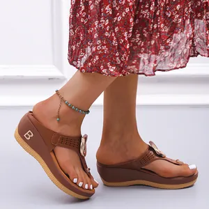 Detailed side view of brown wedge flip-flop sandals with metal B logo and rhinestones