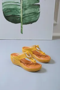 Side detail of yellow wedge flip-flop sandals with perforated straps and metal B accent.