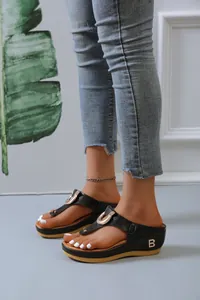 Close-up view of black platform thong sandals with gold B logo detail on model's feet
