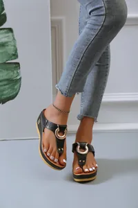 Close-up of black platform thong sandals featuring gold ring and hollow design details