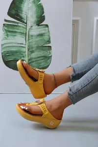Detail view of yellow platform flip-flops with hollow straps and metal B logo detail.