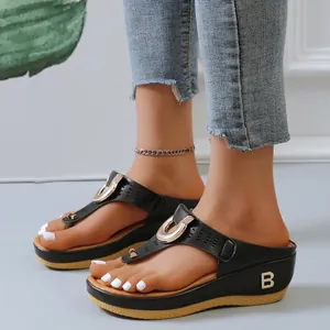Detail view of black platform wedge flip-flops with gold B logo and laser-cut strap