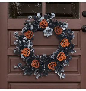 Halloween wreath with black eucalyptus leaves and orange glitter pumpkins on a door