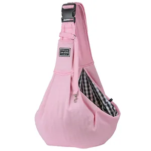 Close-up detail of pink pet sling carrier with checkered lining and adjustable buckle strap.