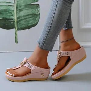 Close-up of pink wedge flip-flops with gold B ornament and cutout details on feet.