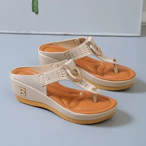 Detail view of beige wedge flip-flop sandals with hollow-out design and metal B logo