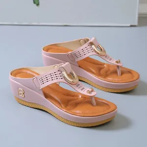 Close-up of pink wedge thong sandals with gold horseshoe buckle and B logo details