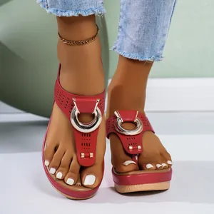 Close-up of red platform thong sandals with metallic ring and laser-cut details