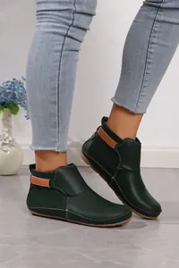 Seitenansicht dunkelgrüner Leder-Stiefeletten mit Kontrastnähten und braunem Riemen.