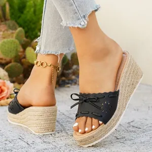 Vista dettagliata di sandali espadrillas neri con zeppa e fiocco e fiori traforati