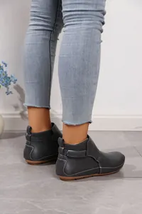 Detailansicht grauer flacher Stiefeletten mit weißen Nähten und Klettverschluss-Riemen