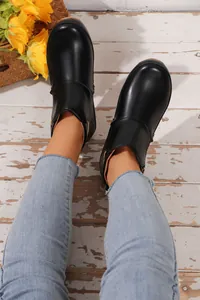 Draufsicht auf schwarze Lederstiefeletten mit hellblauen Jeans auf Holzhintergrund