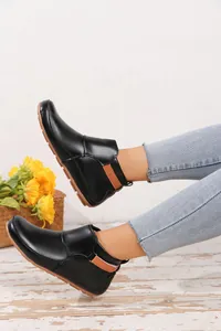 Detailansicht von schwarzen flachen Damen-Stiefeletten mit Klettverschluss am Fuß