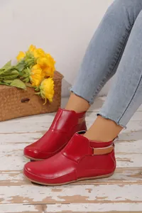 Seitenansicht glänzender roter Lackleder-Stiefeletten am Fuß des Models