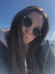 Close-up of vintage polygonal sunglasses with metal frames on a model at beach.