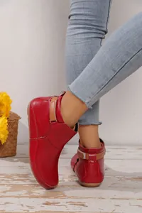 Detailaufnahme von roten Lackleder-Stiefeletten für Damen mit braunem Klettverschlussband