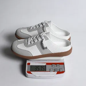 Detailfoto van het gewicht van witte geperforeerde casual muiltjes op een weegschaal.