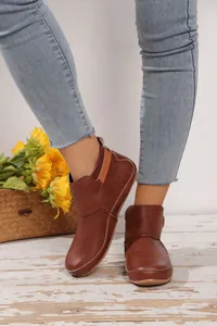 Stylische braune flache Damenstiefeletten aus Leder in gemütlicher Herbststimmung
