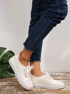 Detail shot of breathable white sneakers with perforated pattern and soft sole.