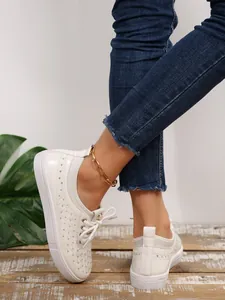 Detail of breathable white microfiber leather sneakers with perforated patterns and soft sole