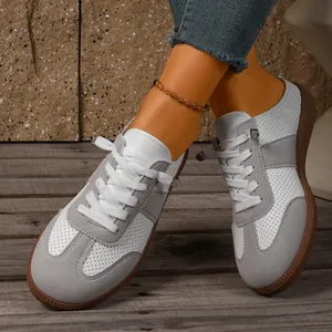 Detailopname van vintage wit-grijze geperforeerde leren sneakers met rubberen zolen