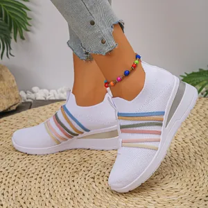 Detailansicht weißer, atmungsaktiver Strick-Keilsneaker mit bunten elastischen Bändern.