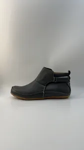 Detailansicht grauer flacher Stiefeletten mit weißen Nähten und verstellbarem Riemen.