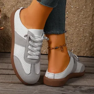 Close-up van witte en grijze geperforeerde sneakers met duurzame bruine rubberen zolen.