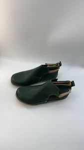 Nahaufnahme von dunkelgrünen flachen Stiefeletten mit beigen Klettverschlüssen.